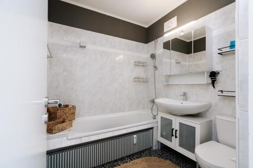 a bathroom with a sink and a tub and a toilet at Panoramic Sierksdorf App A12-1 in Sierksdorf