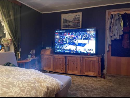 a bedroom with a television on a wooden entertainment center at MOJITO`s ROOM in Lorenskog