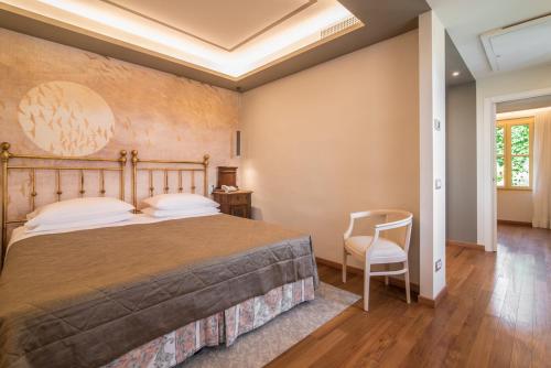 a bedroom with a large bed and a chair at Terme Preistoriche Resort & Spa in Montegrotto Terme