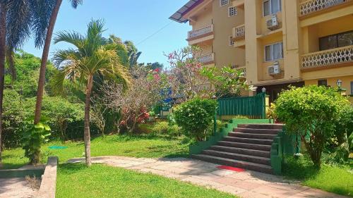 a building with stairs and palm trees in a park at Golden Landmark Green Valley Beach Resort in Dona Paula