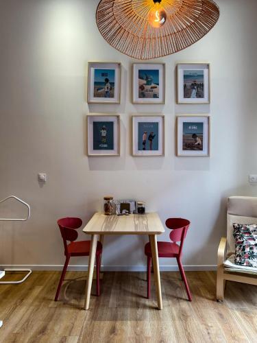 une table et des chaises dans une pièce avec des photos sur le mur dans l'établissement Studio Indépendant, à Ouistreham