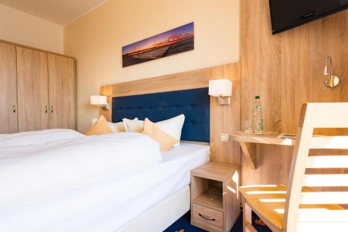 a bedroom with a bed and a desk and a television at Hotel Boddenhus Garni in Zingst