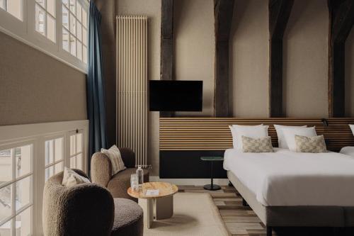 a hotel room with a bed and chairs and a tv at Adam's Canal House in Amsterdam