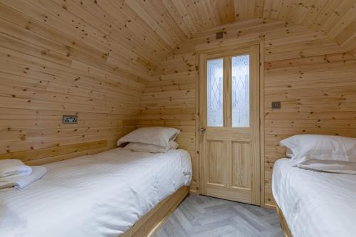 two beds in a log cabin with a window at The Lodge at Brambles Farm in Upper Hulme