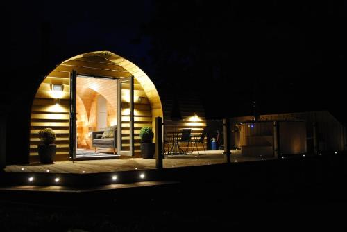a small house with an open door at night at The Lodge at Brambles Farm in Upper Hulme