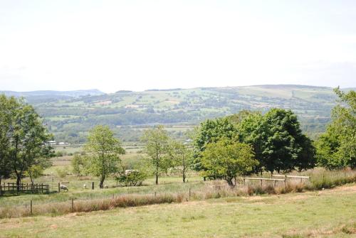 a field of grass with trees in the distance at The Lodge at Brambles Farm in Upper Hulme