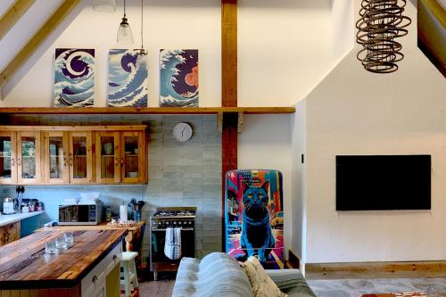 Una sala de estar con un sofá y un televisor en una pared. en Magical Cabin in the Woods, en Kleinbaai