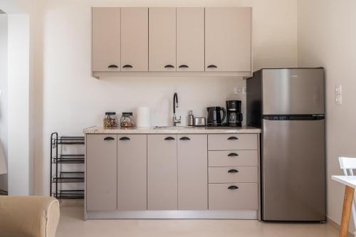 a kitchen with white cabinets and a stainless steel refrigerator at Cuckoos House in Aegina Town