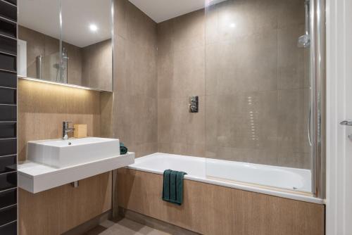 a bathroom with a sink and a bath tub at Montana Apartment - Modern Comfort & Prime Location in London