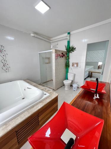 a bathroom with a large white tub and a red sink at Balanço do Mar - Suítes in Prado