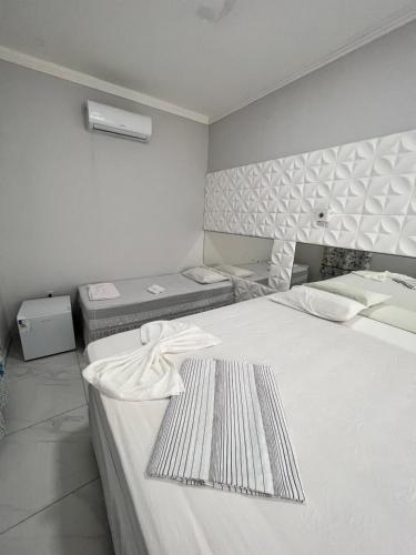 a white room with two beds and two bedsskirts at Balanço do Mar - Suítes in Prado