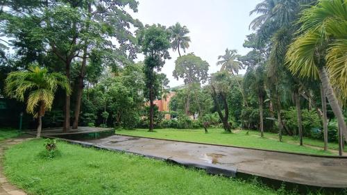 a park with palm trees and a path at Golden Landmark Green Valley Beach Resort in Dona Paula
