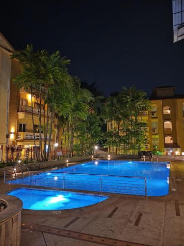a swimming pool at night with palm trees and buildings at Golden Landmark Green Valley Beach Resort in Dona Paula