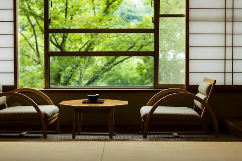 two chairs and a table in front of a window at Hakone Yumoto Onsen Hotel Kajikaso in Hakone