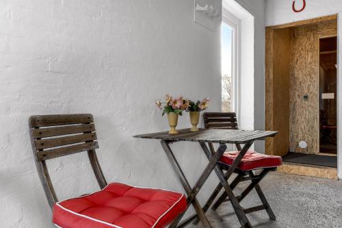 a table with two chairs and a table with flowers on it at Lovely Holiday House With 4 Rooms Close To The North Sea in Frøstrup