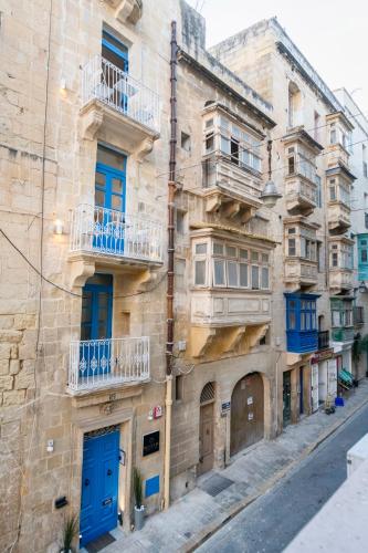 an old building with blue doors and balconies on a street at Mandera's Boutique Suites & Dorms in Valletta