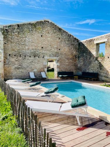 une piscine avec des chaises longues et un mur en briques dans l'établissement Grande chambre privée au Domaine Laroze, à Dieulivol