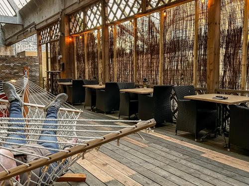 a person laying in a hammock in a restaurant at Weaving Mill Hotel Suites And Shared Kitchen in Oss