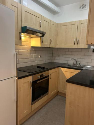 a kitchen with wooden cabinets and black counter tops at Prime Location Flats in London