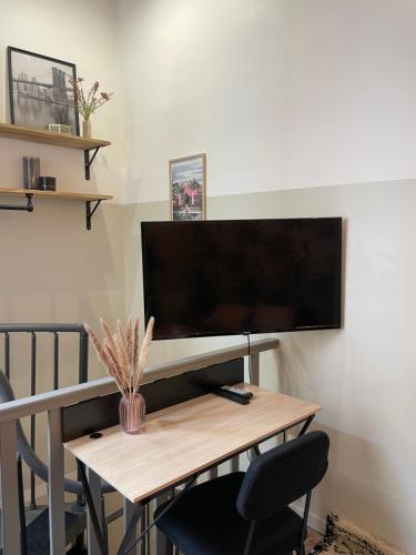 une pièce avec un bureau avec une télévision sur un mur dans l'établissement T1 Duplex Cosy - Notre-Dame - Netflix, à Montauban