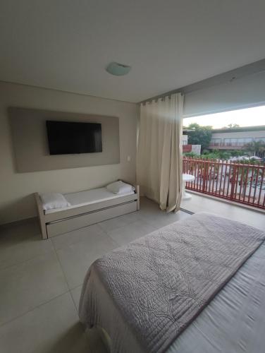 a bedroom with a bed and a tv and a balcony at Flat Île de Pipa Bianco - by Guga in Pipa