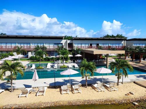 a resort with a swimming pool with chairs and umbrellas at Flat Île de Pipa Bianco - by Guga in Pipa