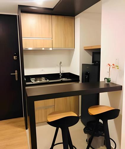 a kitchen with a black counter and two stools at Domus Suites Chia in Chía