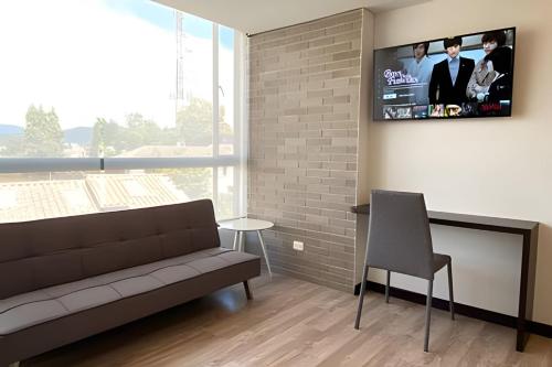 a living room with a couch and a tv on a wall at Domus Suites Chia in Chía