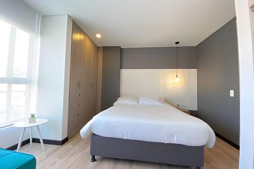 a bedroom with a large white bed and a table at Domus Suites Chia in Chía