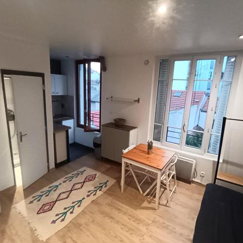 Il comprend un petit salon avec une table et une cuisine. dans l'établissement Studio porte de Paris, à Bagnolet