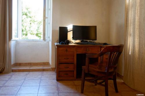 a desk with a television and a chair in a room at Maison de maître en pierre de 1831 avec vue sur la mer à Porticcio in Porticcio