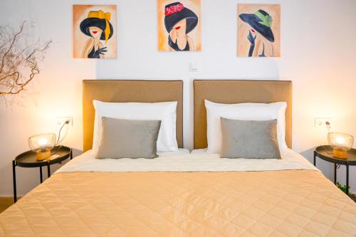 a bed with two pillows and paintings on the wall at 3 Goddesses' studios in Koukounaries