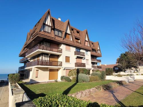 un immeuble d'appartements avec un toit en gambrel dans l'établissement 2 Pièces Résidence EVENTAIL et MER, à Cabourg