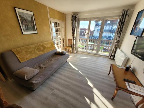 un salon avec un canapé et une grande fenêtre dans l'établissement 2 Pièces Résidence EVENTAIL et MER, à Cabourg