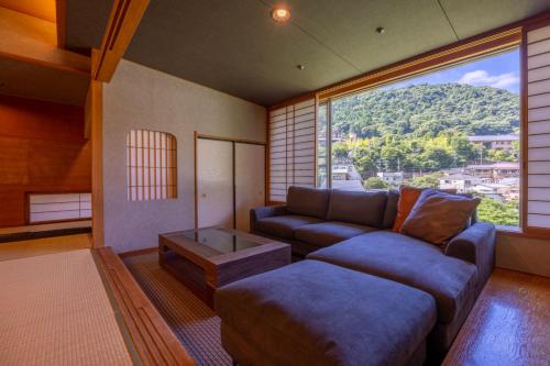 a living room with a couch and a large window at Hakone Yumoto Onsen Hotel Kajikaso in Hakone