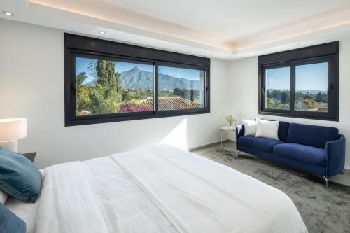 a bedroom with a large bed and a blue couch at Villa Angelique, 5 BDR with Heated Private Pool in Puerto Banus in Marbella