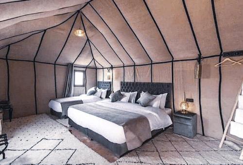 a bedroom with two beds in a tent at Merzouga Queen Luxury Camp in Merzouga