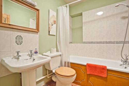 Un baño con lavabo, inodoro y bañera. en Bridge Cottages, Old Post and Bridge Suite, Sleeps 8, en Coniston