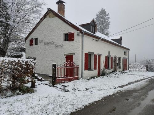 a white house with red doors in the snow at Les Arpents Verts 52 in Momignies