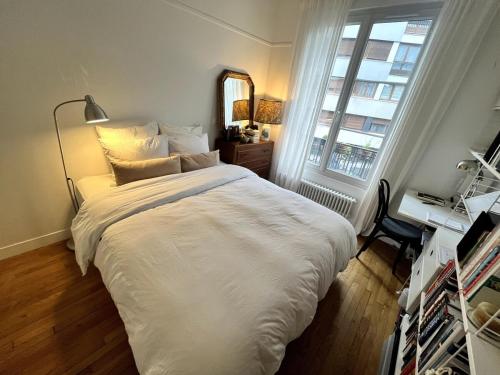 une chambre avec un grand lit blanc et une fenêtre dans l'établissement Romantic Parisian Flat, à Paris