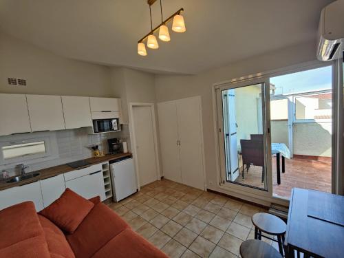 un salon avec un canapé et une cuisine avec une fenêtre dans l'établissement Le cocon méditerranéen, au Barcarès