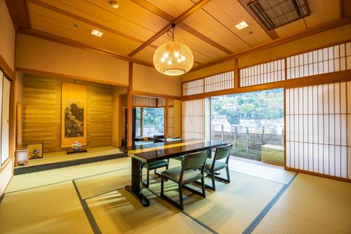a dining room with a table and a large window at Hakone Yumoto Onsen Hotel Kajikaso in Hakone