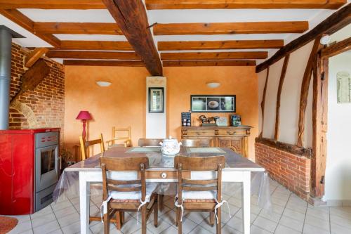 Il comprend une cuisine équipée d'une table, de chaises et d'un réfrigérateur rouge. dans l'établissement La p'tite maison, à Épégard