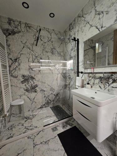 a bathroom with a white sink and a marble wall at Apartman STRONG 2 in Slavonski Brod
