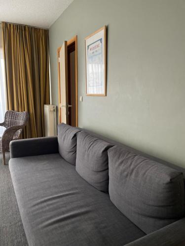 a large gray couch sitting in a living room at Apparthotel De Wielingen in Westende Bad