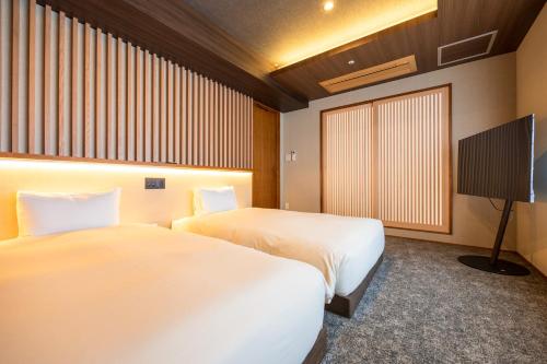a hotel room with two beds and a tv at Hakone Yumoto Onsen Hotel Kajikaso in Hakone