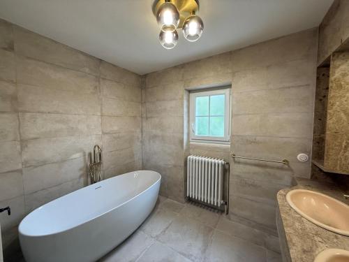 Un baño con una gran bañera blanca y un lavabo. en Domaine de Chevillons, en Chevillon-sur-Huillard