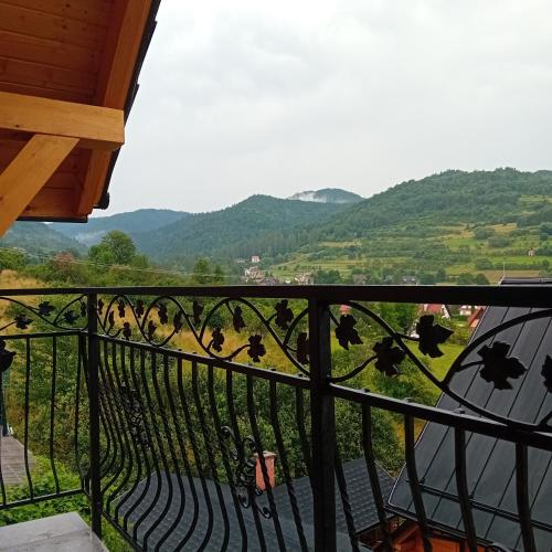 a balcony with a view of a field and mountains at Apartamenty Na Brzegu Szczawnica in Szczawnica
