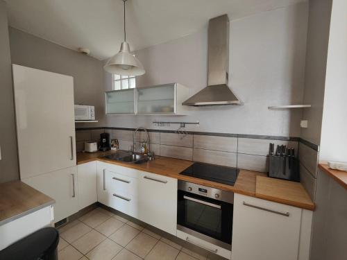 une cuisine avec des armoires blanches et un four à plaques de cuisson dans l'établissement Le nid, 3 chambres proche mer, central, à Saint-Nazaire