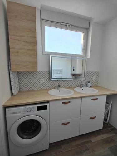 une salle de bain avec deux lavabos et une machine à laver dans l'établissement Le nid, 3 chambres proche mer, central, à Saint-Nazaire